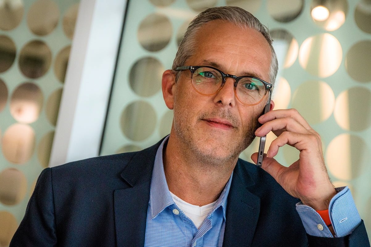 man wearing glasses holding smartphone to his ear listening