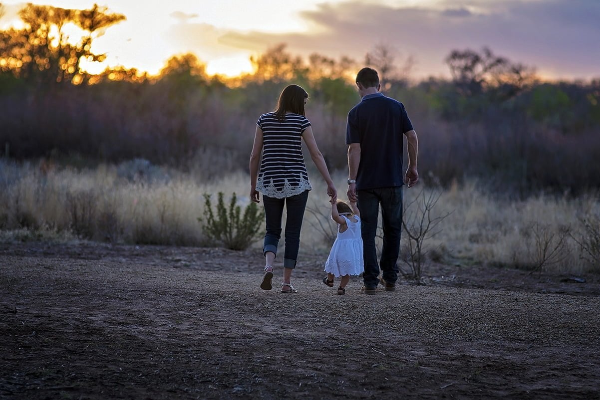 Mother and father walking with young daughter in a field