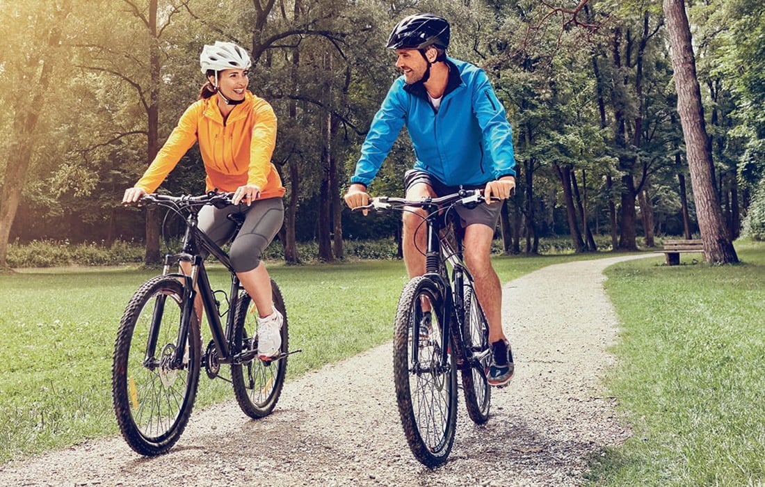 A man and woman riding on the back of a bicycle