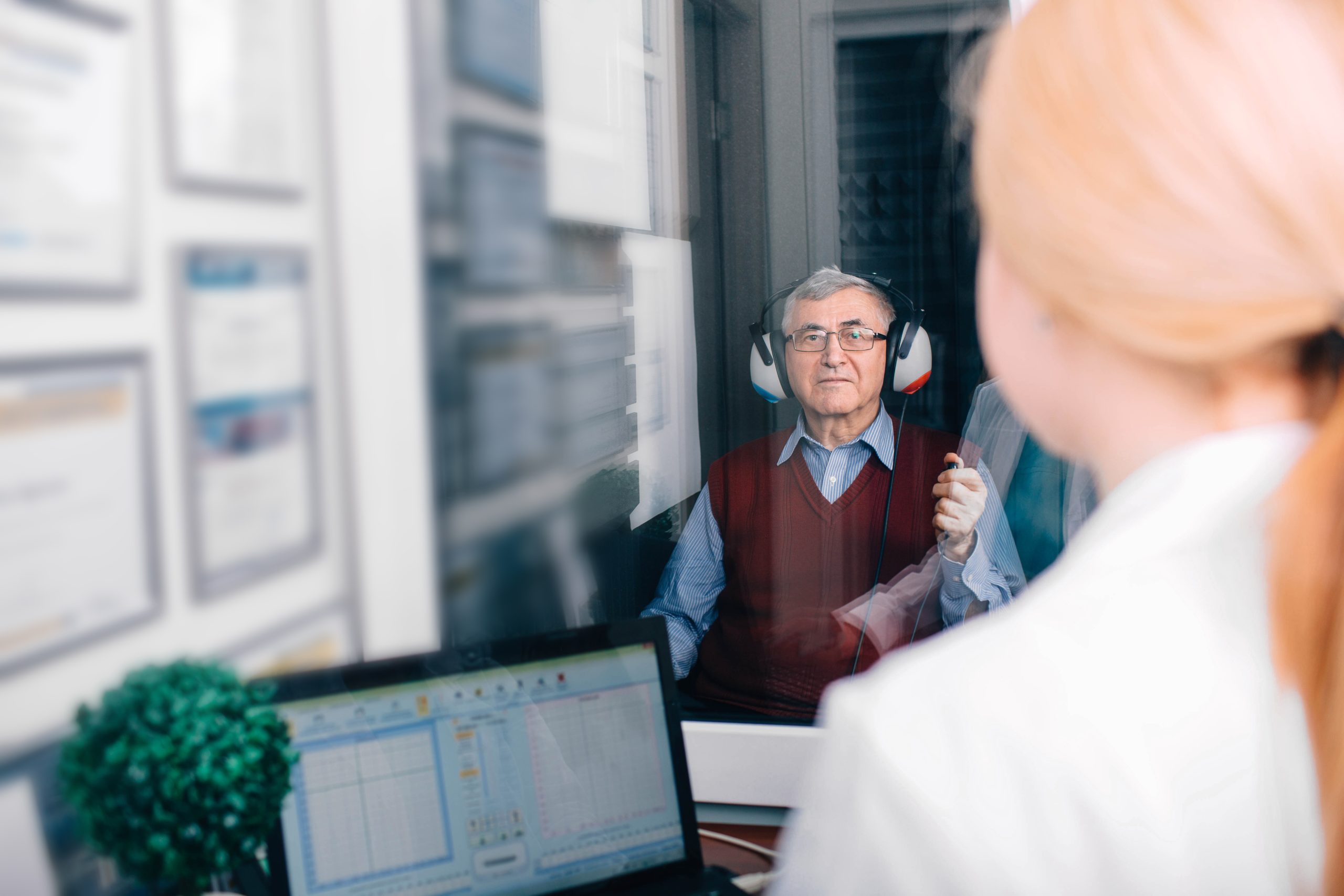 Senior,Man,Getting,A,Hearing,Test,At,A,Doctors,Office, Female doctor holding a hearing instrument testing a little girls ear